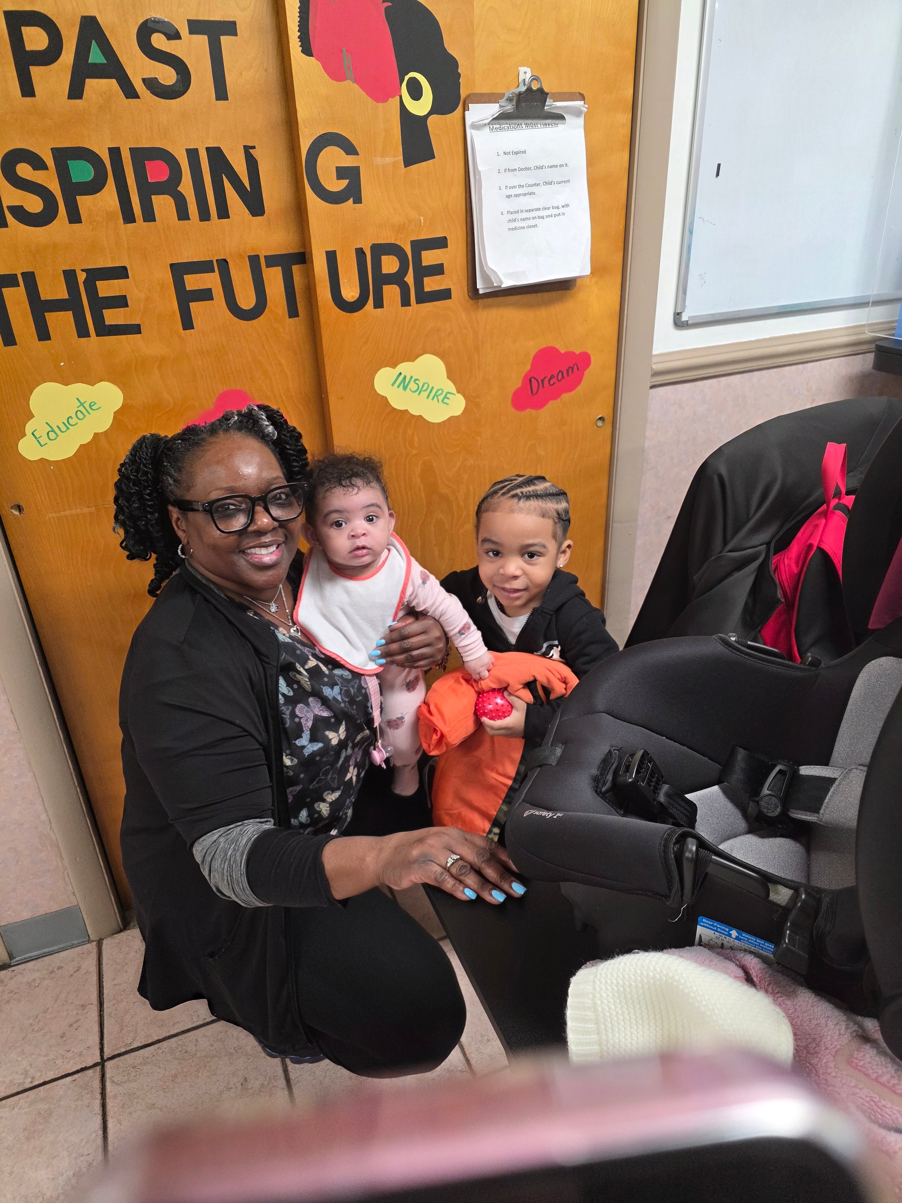 Teacher holding infants in the classroom hallway