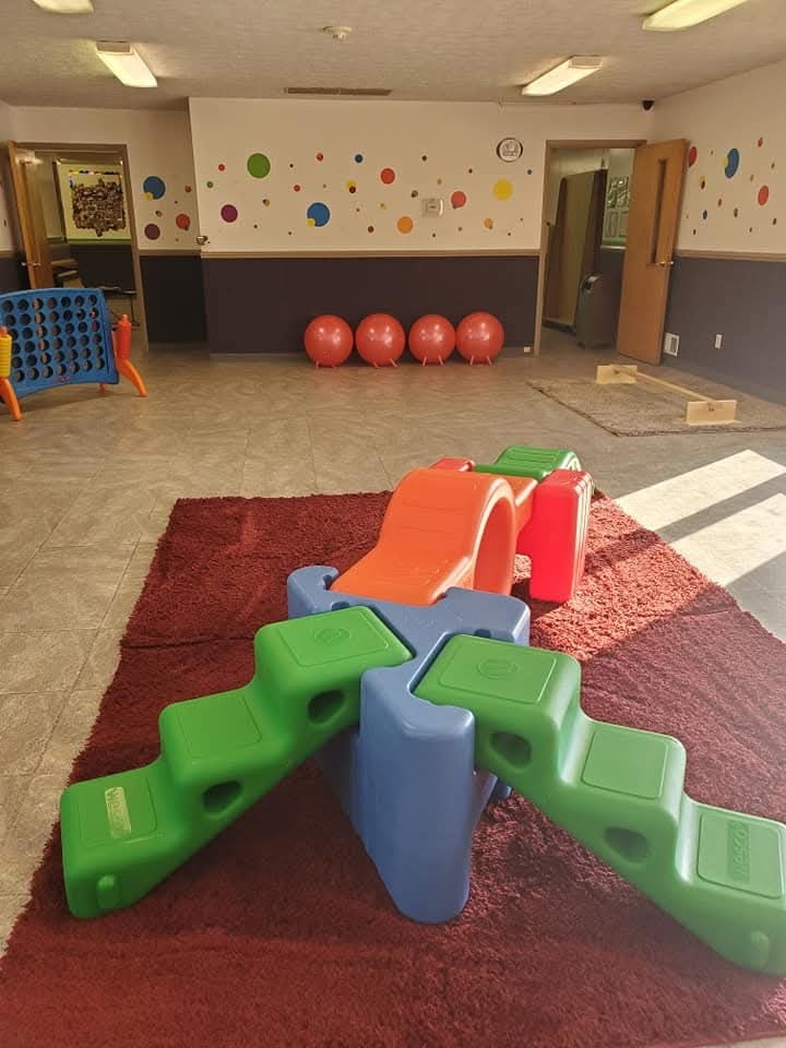 Spacious play area with colorful climbing toys, balance blocks, and polka dot wall decor