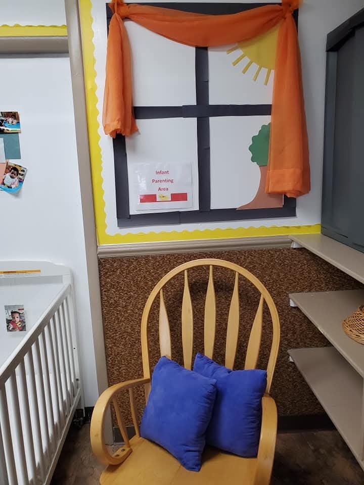 Infant Parenting Area with a rocking chair, crib, and cheerful window bulletin board display
