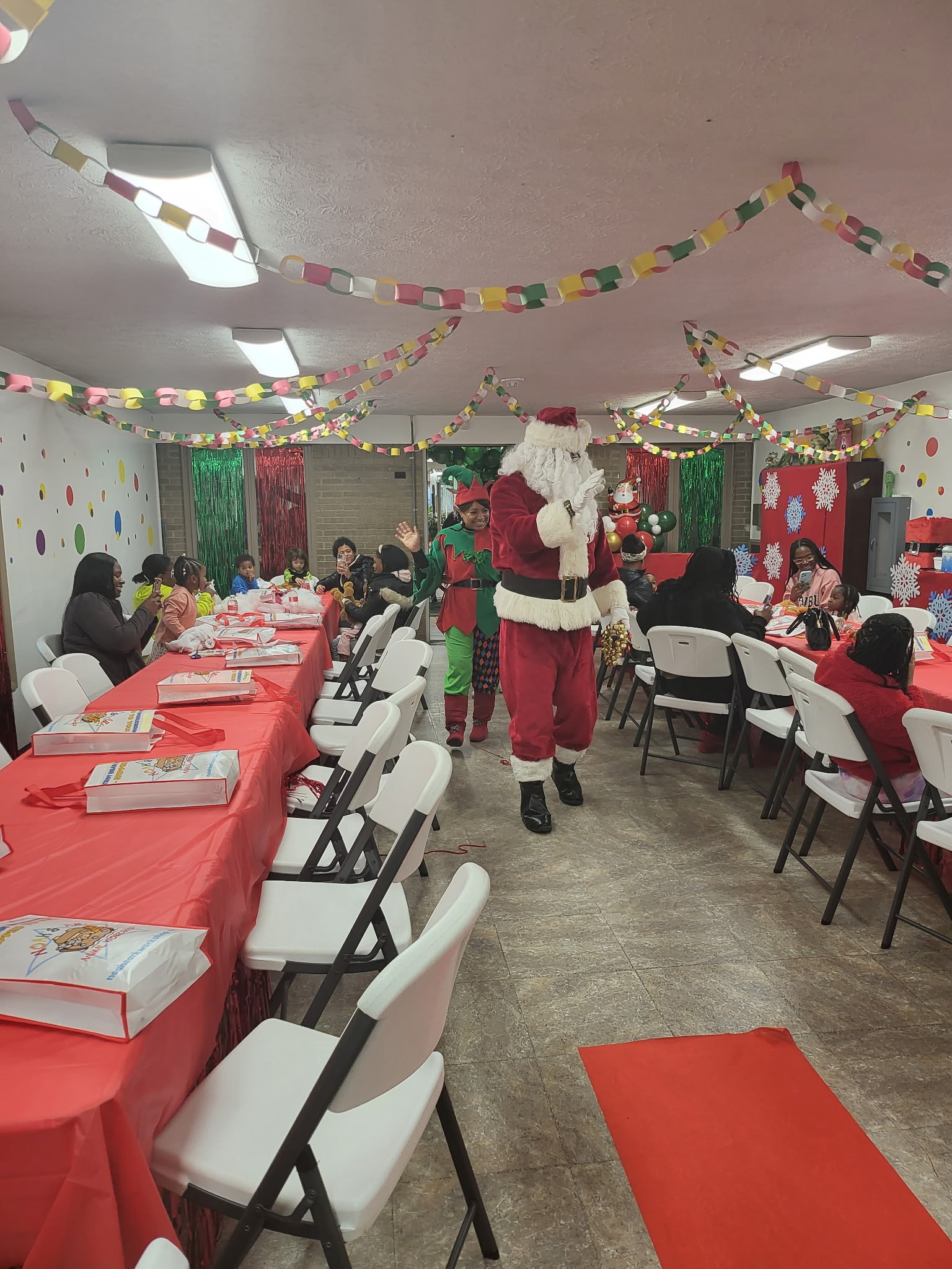 Santa and an elf greeting children and families at the Safecare holiday party